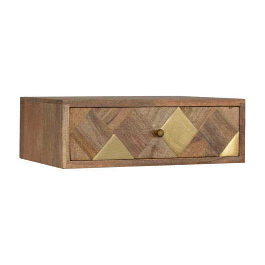 A wall-mounted bedside table with a drawer, featuring a brass inlay pattern and a shiny knob, in an oak-ish finish.