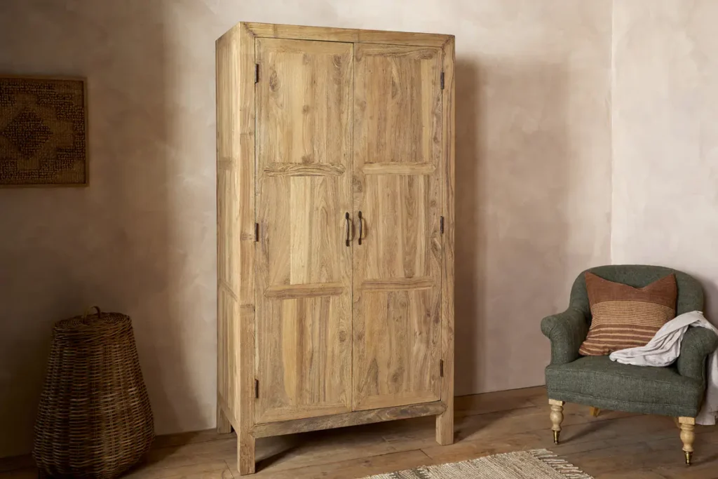 Iya non-toxic furniture reclaimed wood wardrobe in natural unfinished wood colour in a bedroom with an olive green armchair.
