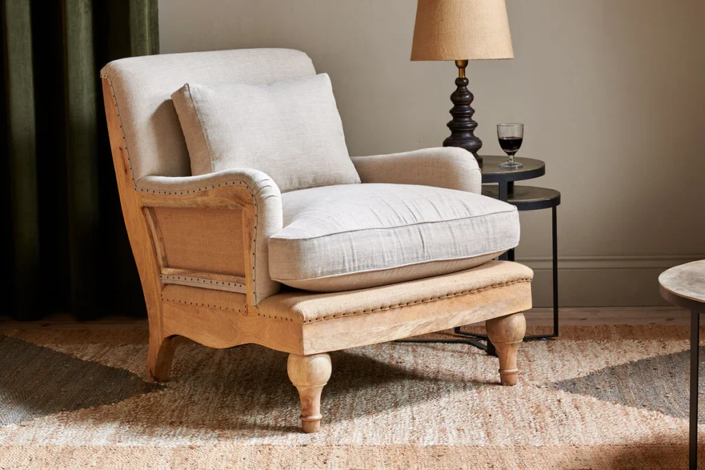 nkuku linen armchair in a stone colour with a brass table lamp beside it