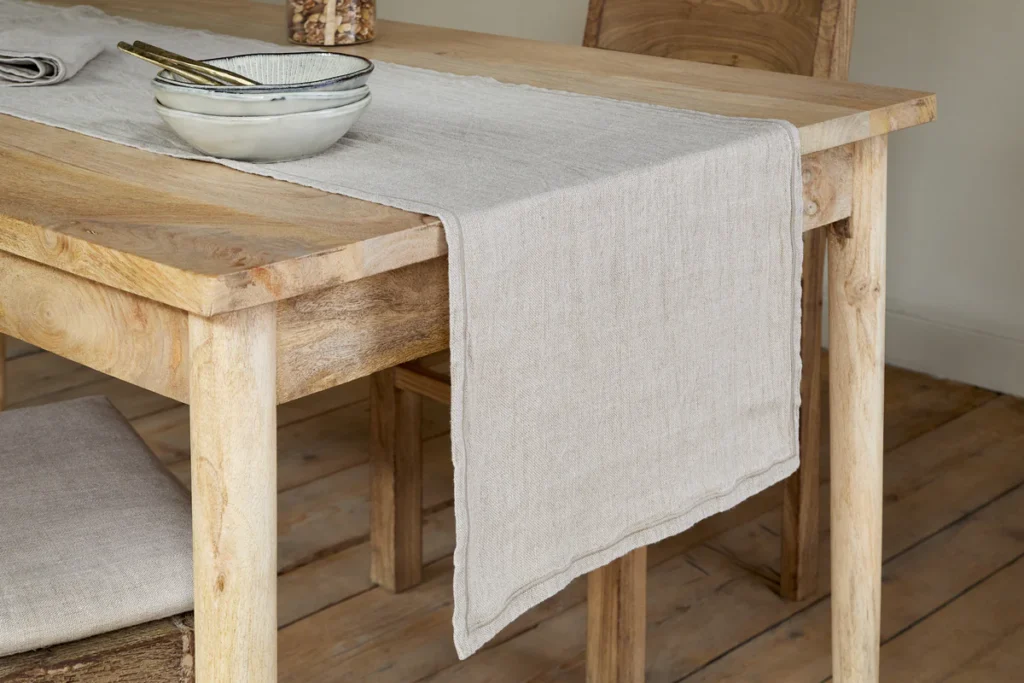 The Honest Nkuku Recycled Glassware Review: We Look At 10 Tumblers, Highballs and Gin Glasses linen tablecloth in a natural beige colour placed on a wooden table with a ceramic bowl