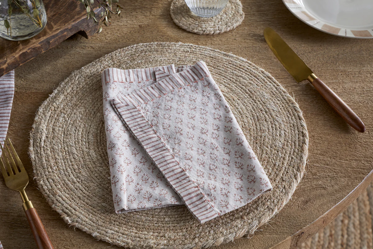 The Honest Nkuku Recycled Glassware Review: We Look At 10 Tumblers, Highballs and Gin Glasses linen napkin with a pink floral pattern set on top of a woven jute placemat