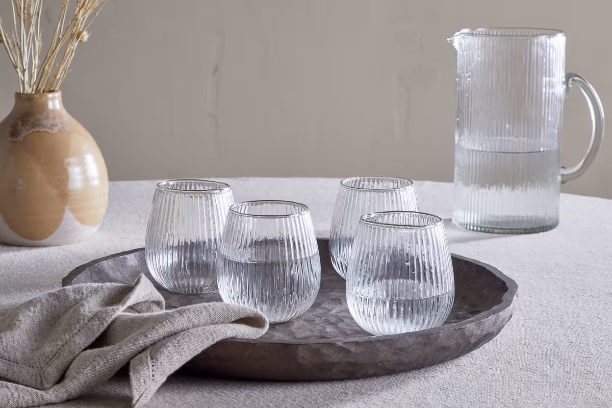 The Honest Nkuku Recycled Glassware Review: We Look At 10 Tumblers, Highballs and Gin Glasses four ridged tumblers set on a grey tray with a linen napkin