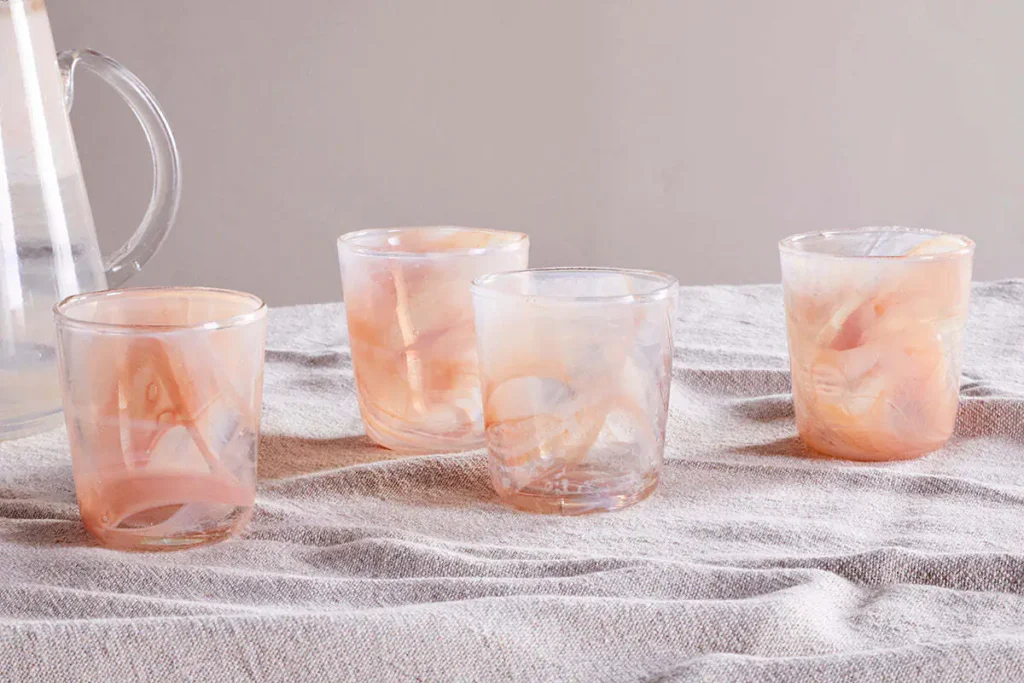 The Honest Nkuku Recycled Glassware Review: We Look At 10 Tumblers, Highballs and Gin Glasses four marble swirl tumbler glasses in an apricot and clear colour