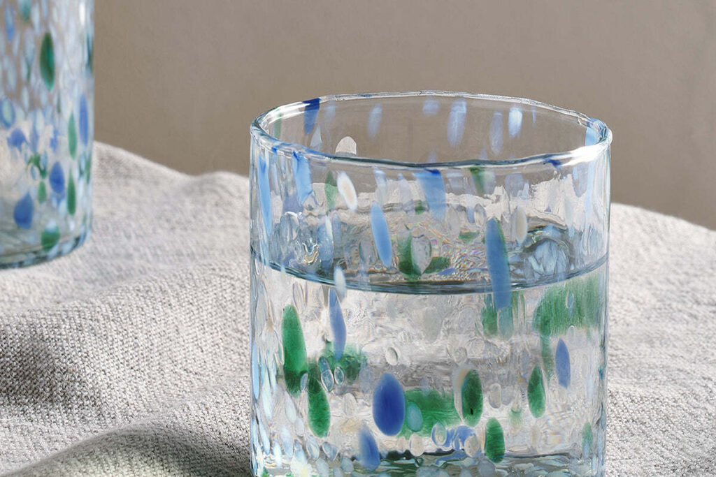 The Honest Nkuku Recycled Glassware Review: We Look At 10 Tumblers, Highballs and Gin Glasses close up shot of a recycled glass tumbler with blue and green flecks through the glass