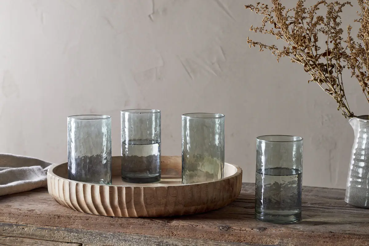 The Honest Nkuku Recycled Glassware Review: We Look At 10 Tumblers, Highballs and Gin Glasses four sage green highball glasses made from recycled glass placed on a wood tray