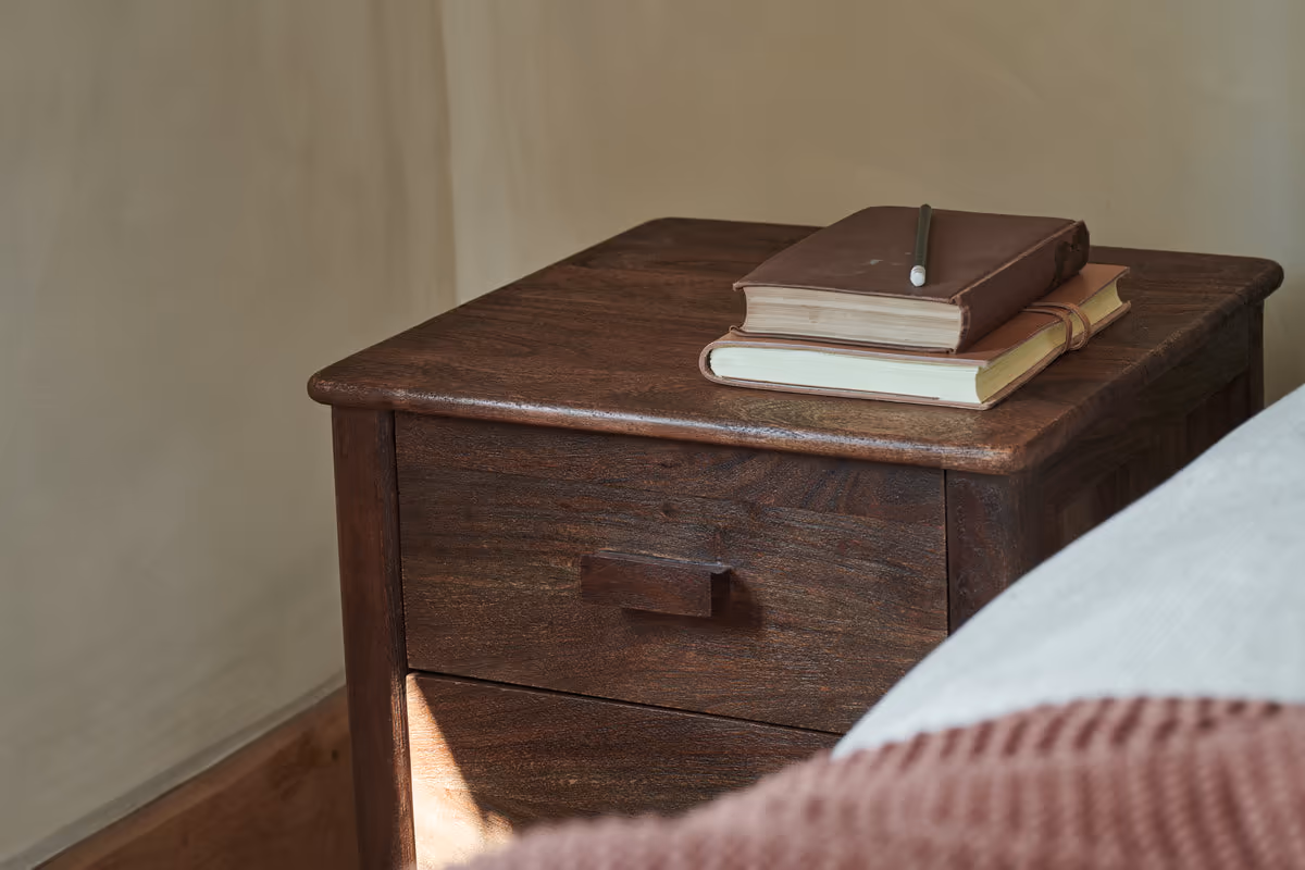 How to Create a Sustainable Bedroom: A Practical Guide Anbu Acacia Bedside Table in Washed Walnut finish with a book on top.