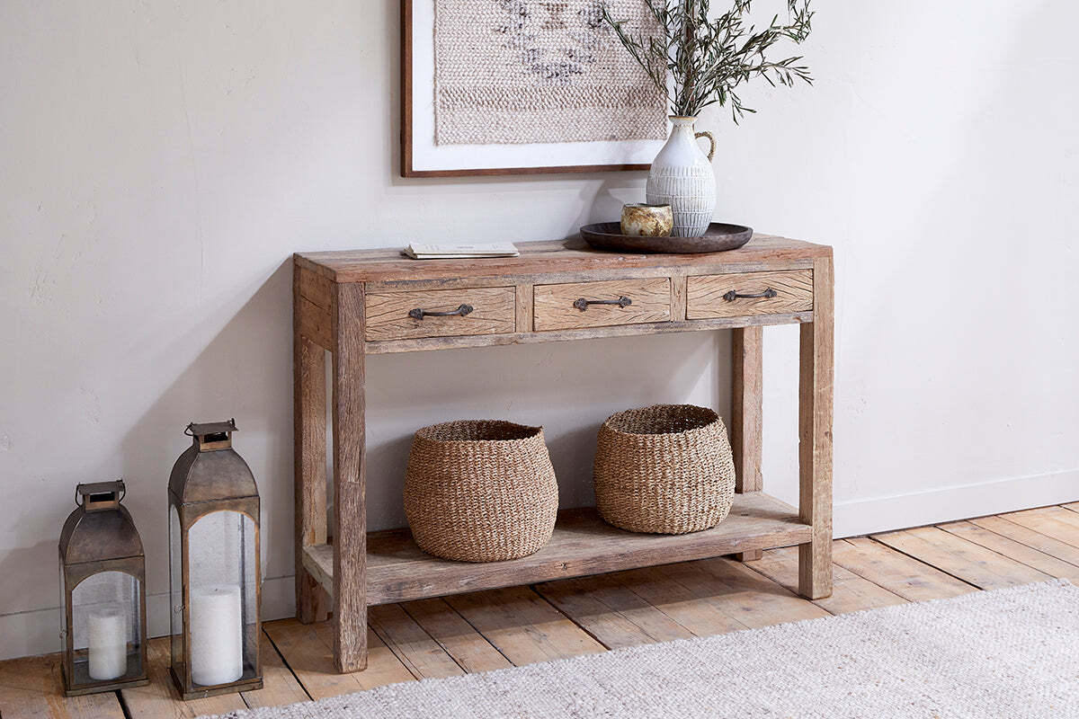 Reclaimed wood 3 drawer console table with two baskets and home decor styled on top.
