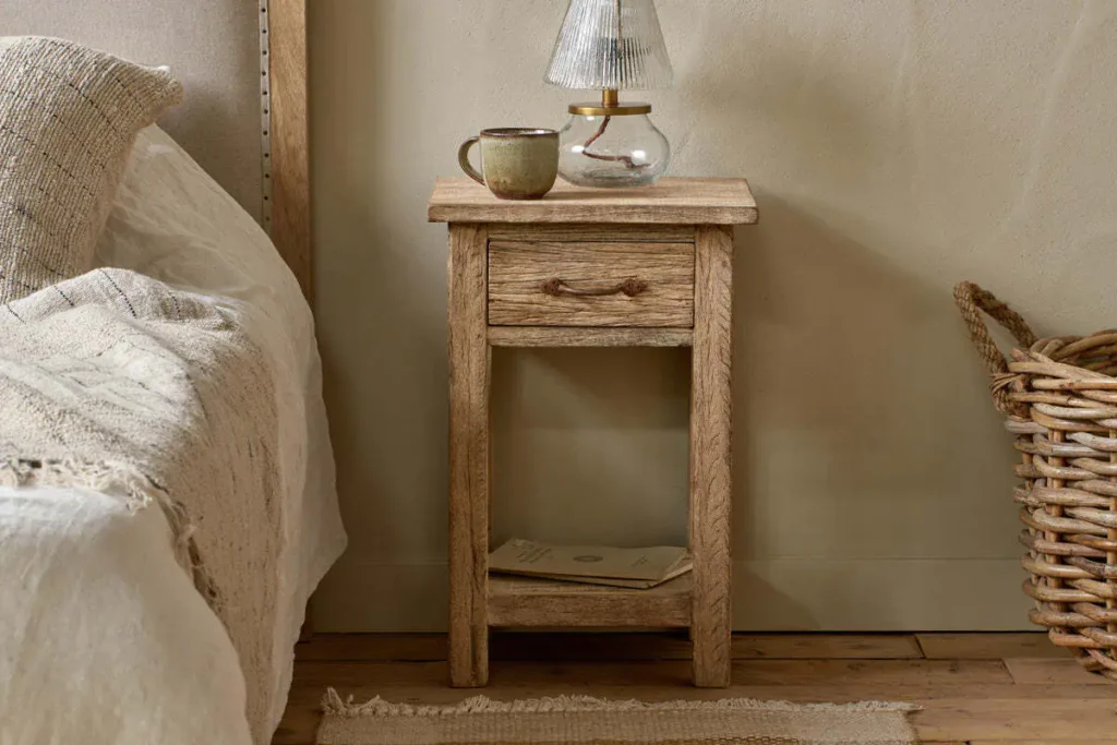 How to Create a Sustainable Bedroom: A Practical Guide Ibo Reclaimed Wood Bedside Table in Natural with a mug and bedside lamp on top beside a bed.