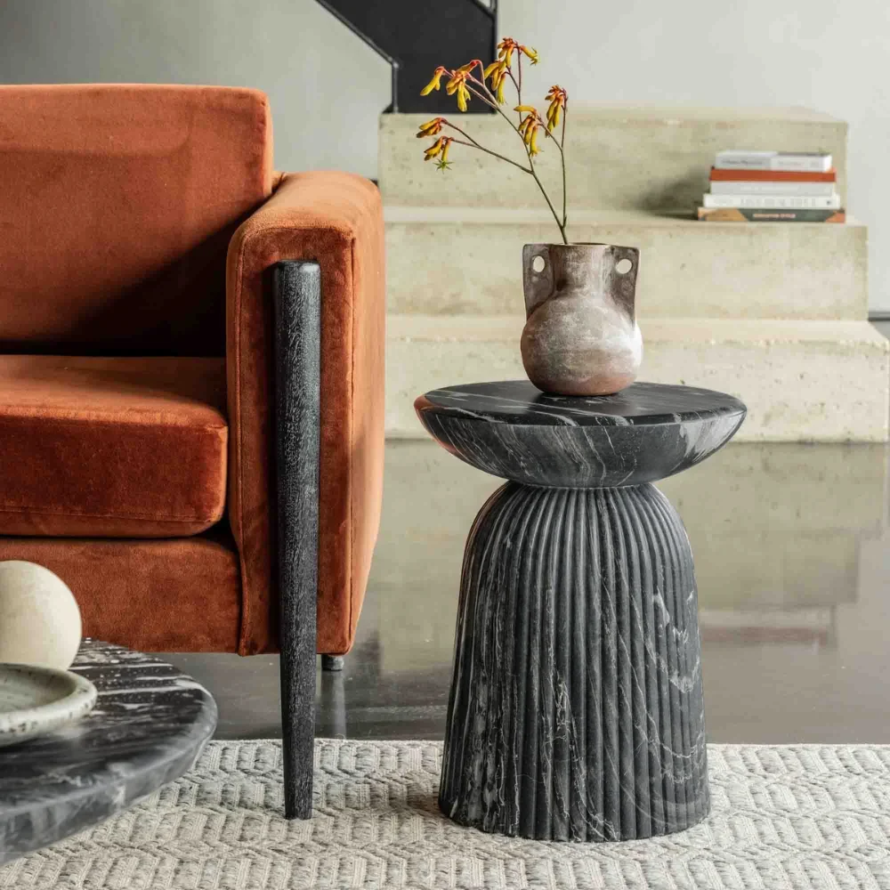 Grey travertine stone side table next to an orange sofa by Atkin and thyme.