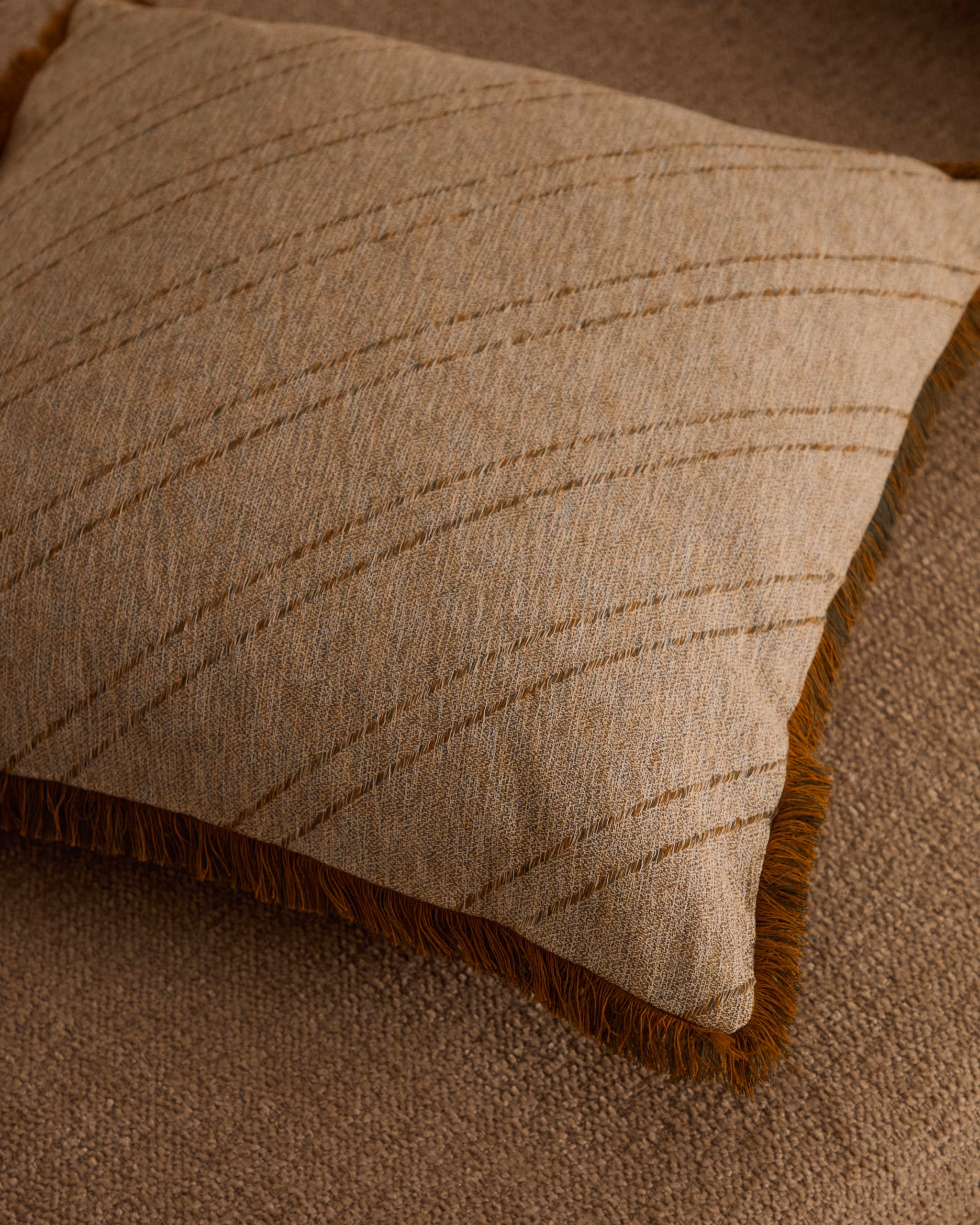 Autumn Winter Home Trends 2026: A Sustainable Edit Beige jacquard cushion cover with orange fringing.