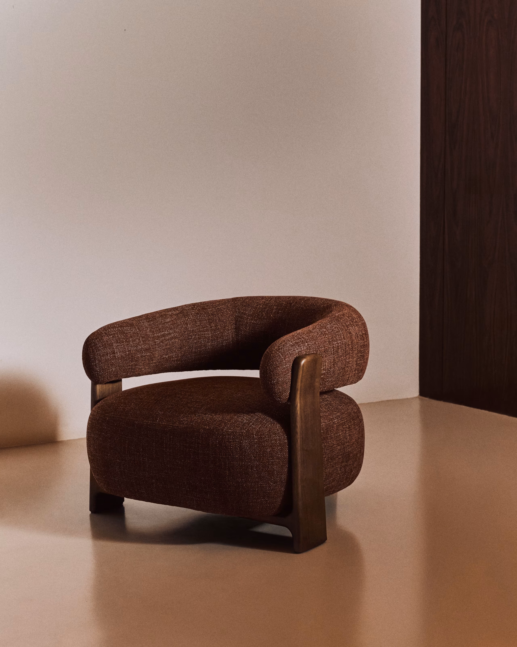 Autumn Winter Home Trends 2026: A Sustainable Edit Fire-retardant armchair in brown chenille and solid ash wood with walnut-coloured finish.