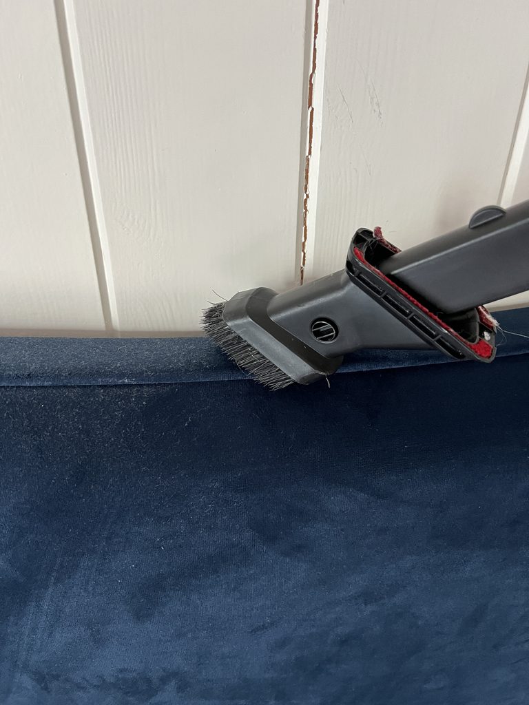 Hoovering a velvet headboard with a fabric attachment on the hoover.