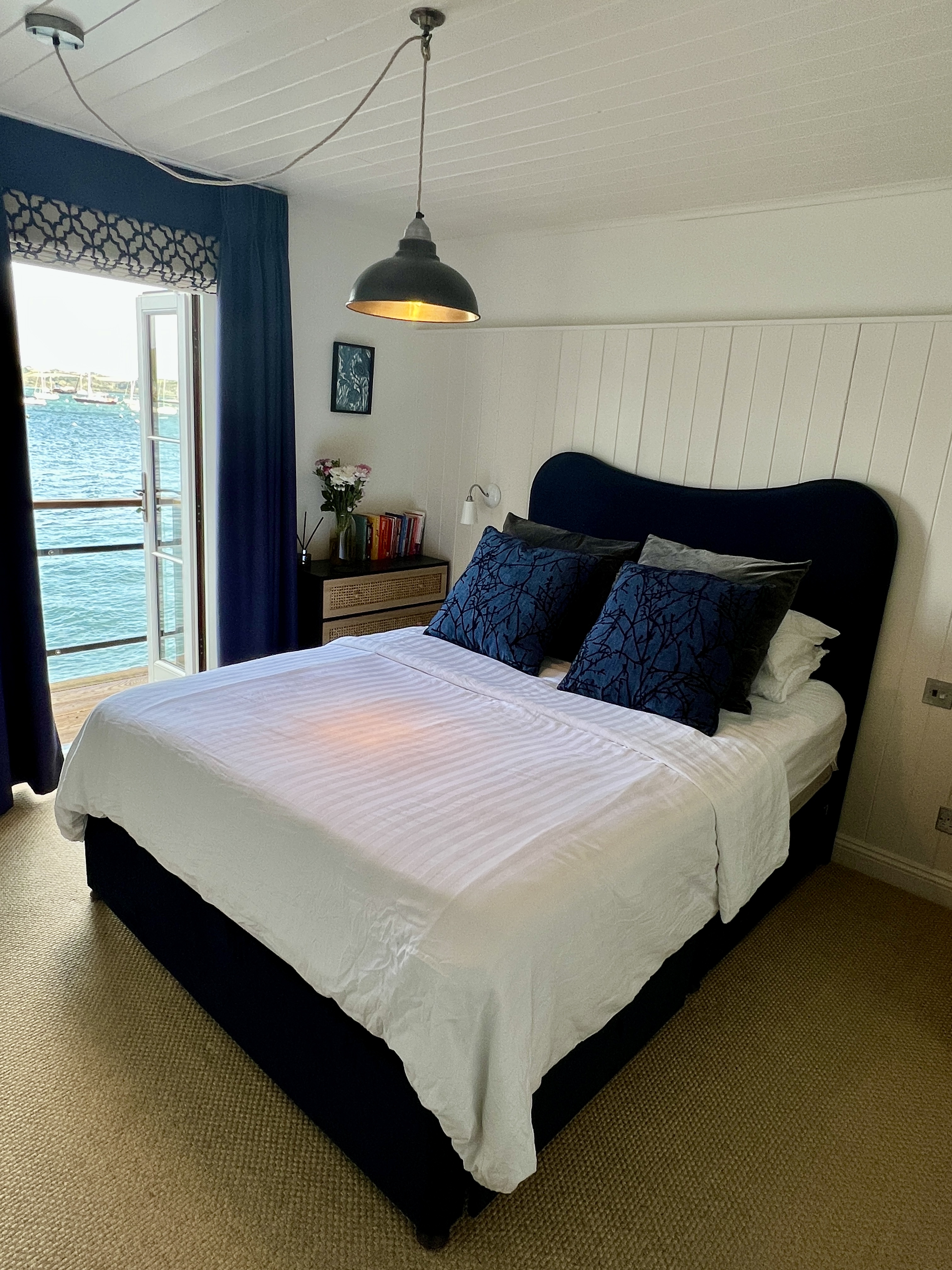 Simba Jesmond Bed Review the Navy Velvet Bed with bedding and a sea view in the background.
