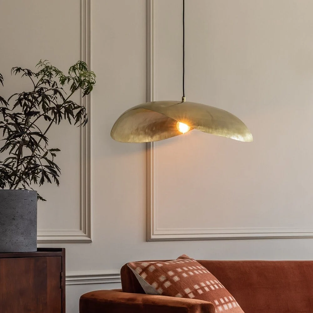Autumn Winter Home Trends 2026: A Sustainable Edit Brass hanging ceiling pendant light with an orange sofa.